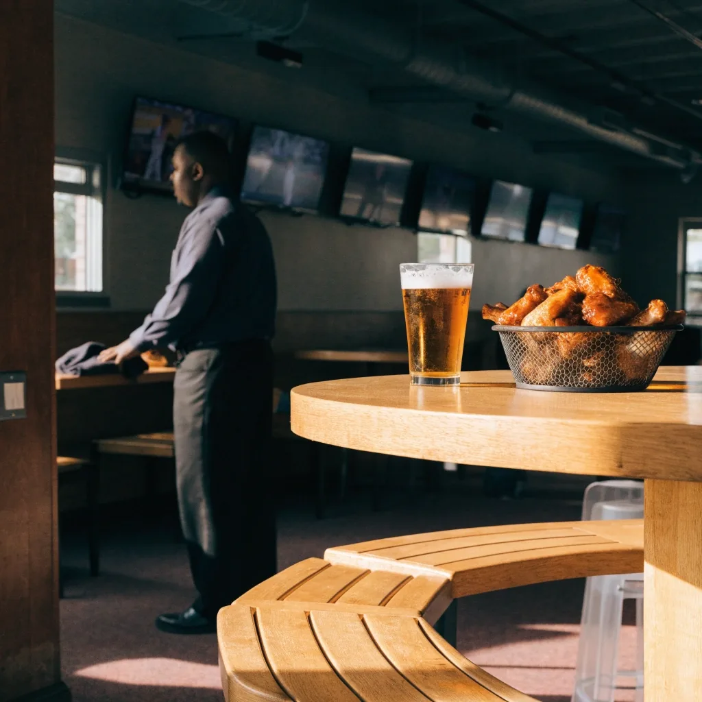 An emptied sports bar at closing time, stools upside down on the bar and one amber lamp still on